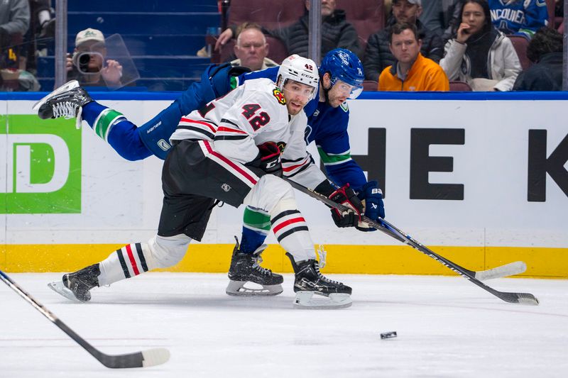 Nov 16, 2024; Vancouver, British Columbia, CAN; Vancouver Canucks forward Jake DeBrusk (74) passes around Chicago Blackhawks defenseman Nolan Allan (42) during the third period at Rogers Arena. Mandatory Credit: Bob Frid-Imagn Images