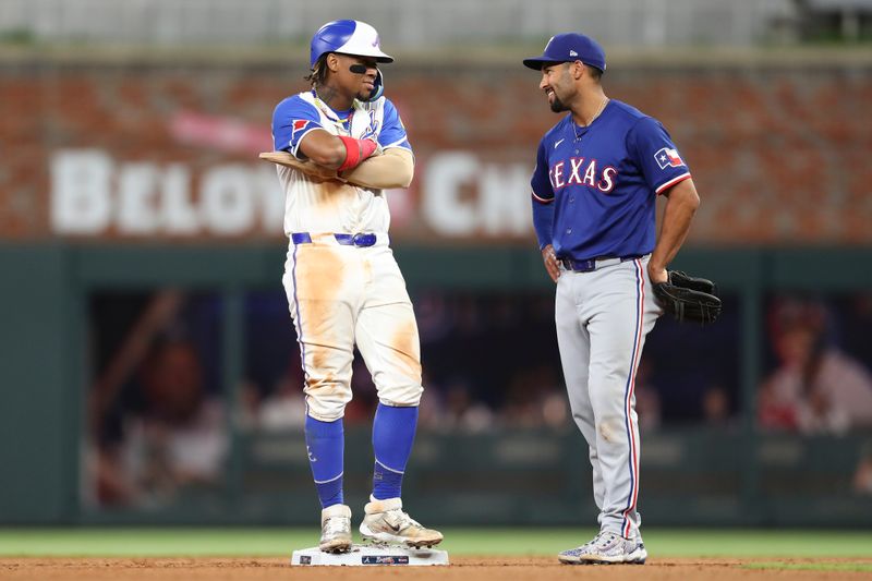 Apr 20, 2024; Cumberland, Georgia, USA;  Atlanta Braves right fielder Ronald Acuna Jr (13) and Texas Rangers second baseman Marcus Semien (2) stand on second base in the eighth inning at Truist Park. Mandatory Credit: Mady Mertens-USA TODAY Sports