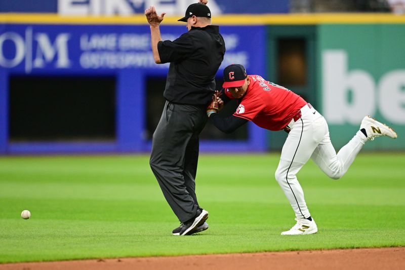 Sep 16, 2024; Cleveland, Ohio, USA; Cleveland Guardians second baseman Andres Gimenez (0) collides with umpire Chad Fairchild while attempting to field a ball hit by Minnesota Twins center fielder Byron Buxton (not pictured) during the third inning at Progressive Field. Mandatory Credit: Ken Blaze-Imagn Images