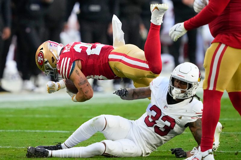 San Francisco 49ers running back Christian McCaffrey, top, falls to the ground over Arizona Cardinals cornerback Antonio Hamilton Sr. (33) during the first half of an NFL football game Sunday, Dec. 17, 2023, in Glendale, Ariz. (AP Photo/Matt York)