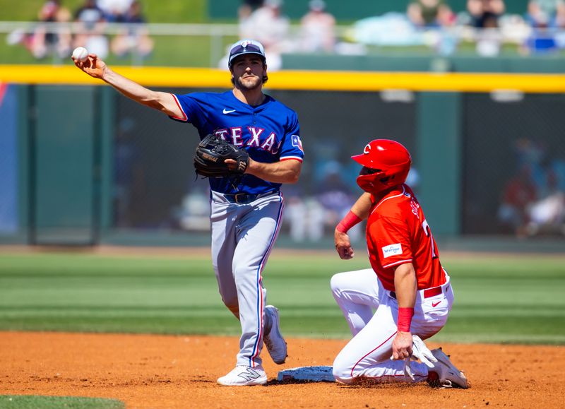 Mar 20, 2024; Goodyear, Arizona, USA; Texas Rangers infielder Josh Smith (left) throws to first base to complete the double play after forcing out sliding base runner Cincinnati Reds base runner Spencer Steer during a spring training baseball game at Goodyear Ballpark. Mandatory Credit: Mark J. Rebilas-USA TODAY Sports