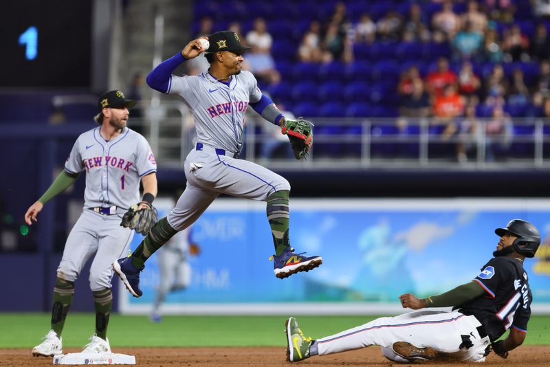 May 17, 2024; Miami, Florida, USA; New York Mets shortstop Francisco Lindor (12) turns a double play as Miami Marlins designated hitter Bryan De La Cruz (14) slides at second base during the first inning at loanDepot Park. Mandatory Credit: Sam Navarro-USA TODAY Sports