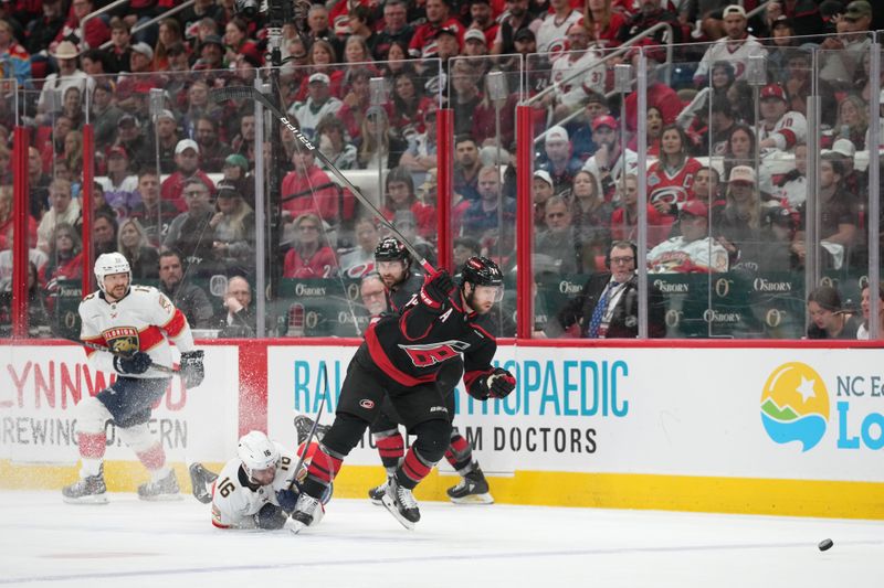 May 22, 2025; Raleigh, North Carolina, USA;  Carolina Hurricanes defenseman Jaccob Slavin (74) chases a loose puck against Florida Panthers forward Aleksander Barkov (16) during the first period in game two of the Eastern Conference Final of the 2025 Stanley Cup Playoffs at Lenovo Center. Mandatory Credit: James Guillory-Imagn Images
