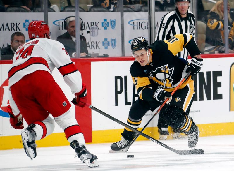 Oct 18, 2024; Pittsburgh, Pennsylvania, USA;  Pittsburgh Penguins right wing Jesse Puljujarvi (18) moves the puck against Carolina Hurricanes defenseman Jaccob Slavin (74) during the third period at PPG Paints Arena. Mandatory Credit: Charles LeClaire-Imagn Images