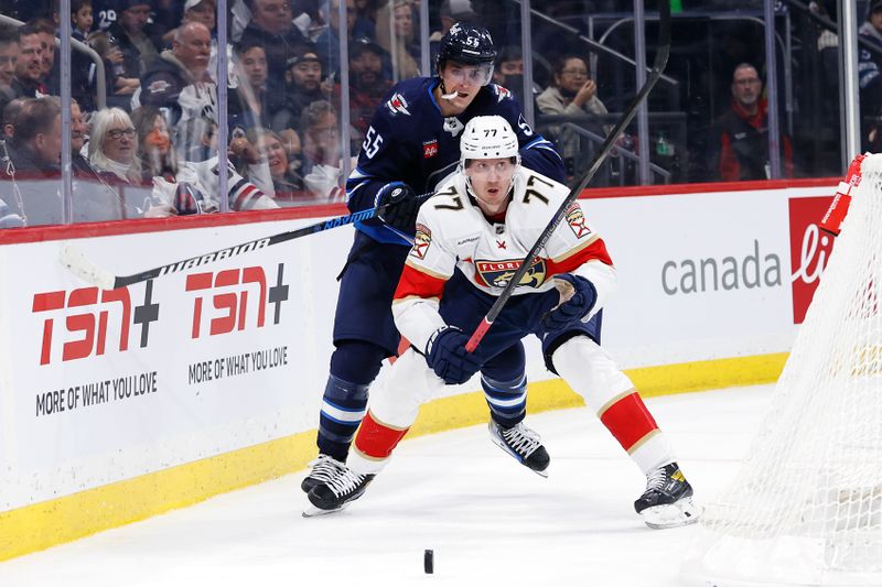 Nov 19, 2024; Winnipeg, Manitoba, CAN; Winnipeg Jets center Mark Scheifele (55) and Florida Panthers defenseman Niko Mikkola (77) chase after the puck ointhe second period at Canada Life Centre. Mandatory Credit: James Carey Lauder-Imagn Images