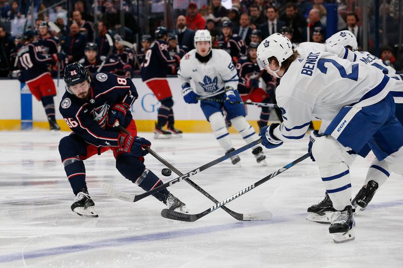 Dec 29, 2023; Columbus, Ohio, USA; Columbus Blue Jackets right wing Kirill Marchenko (86) chips the puck over the stick of Toronto Maple Leafs defenseman Simon Benoit (2) during the first period at Nationwide Arena. Mandatory Credit: Russell LaBounty-USA TODAY Sports