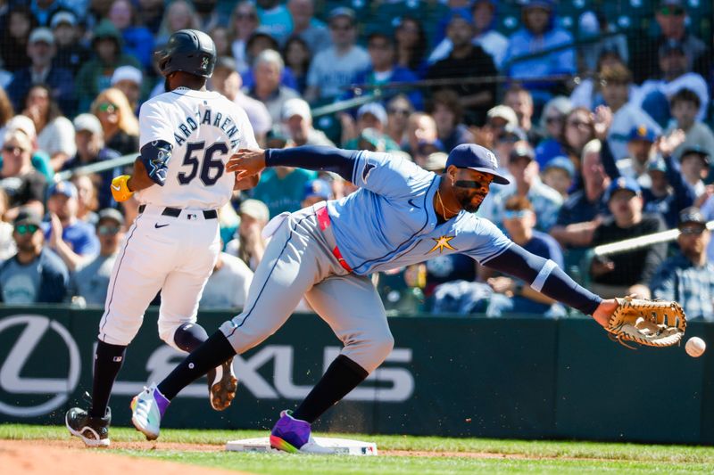 Aug 28, 2024; Seattle, Washington, USA; Tampa Bay Rays first baseman Yandy Diaz (2) reaches for a throw wide of the bag on a bunt-single by Seattle Mariners left fielder Randy Arozarena (56) during the second inning at T-Mobile Park. Arozarena advanced to second base on the throwing error. Mandatory Credit: Joe Nicholson-USA TODAY Sports