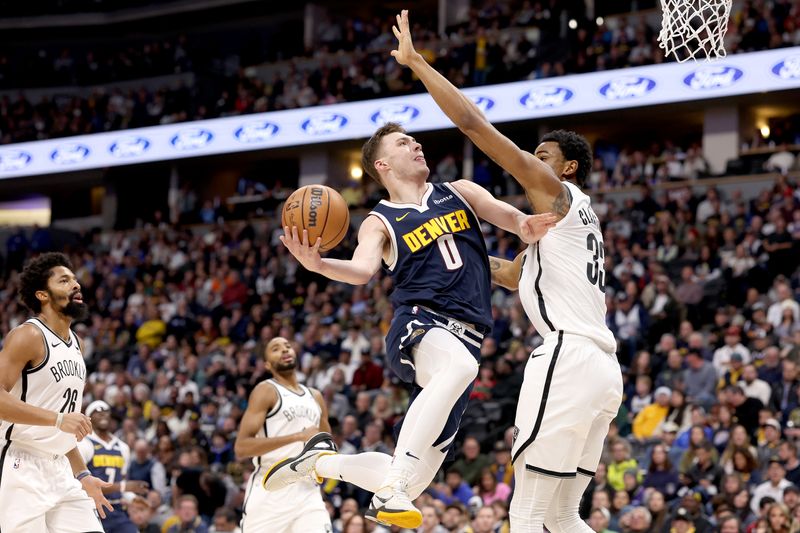 DENVER, COLORADO - DECEMBER 14: Christian Braun #0 of the Denver Nuggets goes to the basket against Nic Claxton #33 of the Brooklyn Nets in the second quarter at Ball Arena on December 14, 2023 in Denver, Colorado. NOTE TO USER: User expressly acknowledges and agrees that, by downloading and or using this photograph, User is consenting to the terms and conditions of the Getty Images License Agreement.   (Photo by Matthew Stockman/Getty Images)