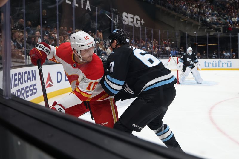 Oct 30, 2024; Salt Lake City, Utah, USA; Calgary Flames center Jonathan Huberdeau (10) and Utah Hockey Club left wing Lawson Crouse (67) battle for the puck during the third period at Delta Center. Mandatory Credit: Rob Gray-Imagn Images