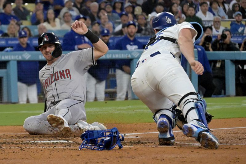 May 20, 2024; Los Angeles, California, USA;  Arizona Diamondbacks shortstop Kevin Newman (18) beats the tag by Los Angeles Dodgers catcher Will Smith (16) as he scores on a single by designated hitter Joc Pederson (3) in the third inning at Dodger Stadium. Mandatory Credit: Jayne Kamin-Oncea-USA TODAY Sports