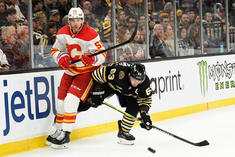 Feb 6, 2024; Boston, Massachusetts, USA; Calgary Flames defenseman Noah Hanifin (55) clears the puck away from Boston Bruins left wing Brad Marchand (63) during the third period at TD Garden. Mandatory Credit: Bob DeChiara-USA TODAY Sports