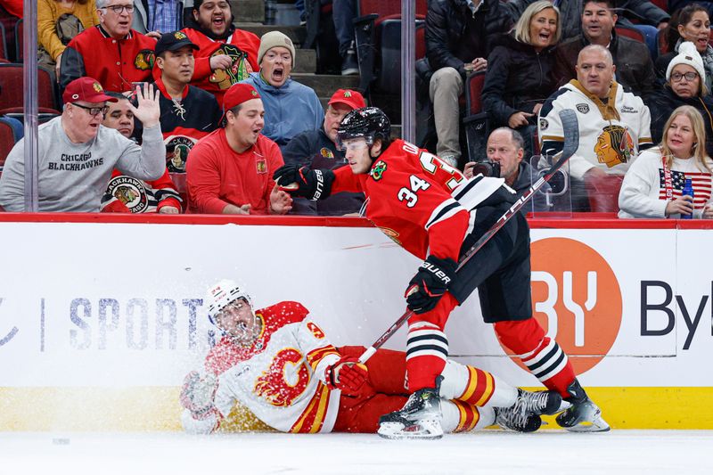 Nov 18, 2025; Chicago, Illinois, USA; Chicago Blackhawks center Colton Dach (34) battles for the puck with Calgary Flames defenseman Brayden Pachal (94) during the first period at United Center. Mandatory Credit: Kamil Krzaczynski-Imagn Images