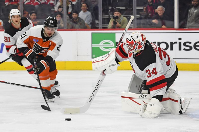 Jan 27, 2025; Philadelphia, Pennsylvania, USA; New Jersey Devils goaltender Jake Allen (34) clears the puck away from Philadelphia Flyers center Scott Laughton (21) during the first period at Wells Fargo Center. Mandatory Credit: Eric Hartline-Imagn Images