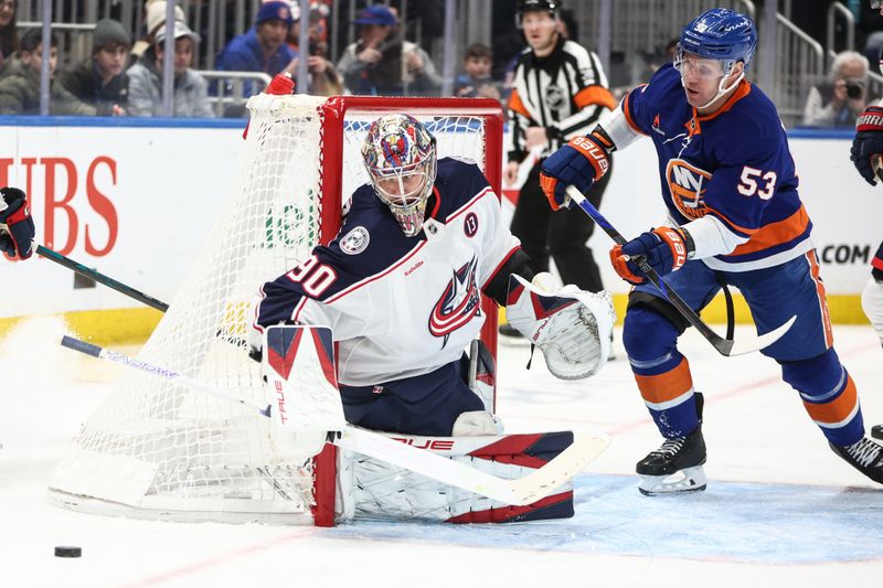 Jan 20, 2025; Elmont, New York, USA;  Columbus Blue Jackets goaltender Elvis Merzlikins (90) deflects the puck after a shot on goal attempt by New York Islanders center Casey Cizikas (53) in the second period at UBS Arena. Mandatory Credit: Wendell Cruz-Imagn Images