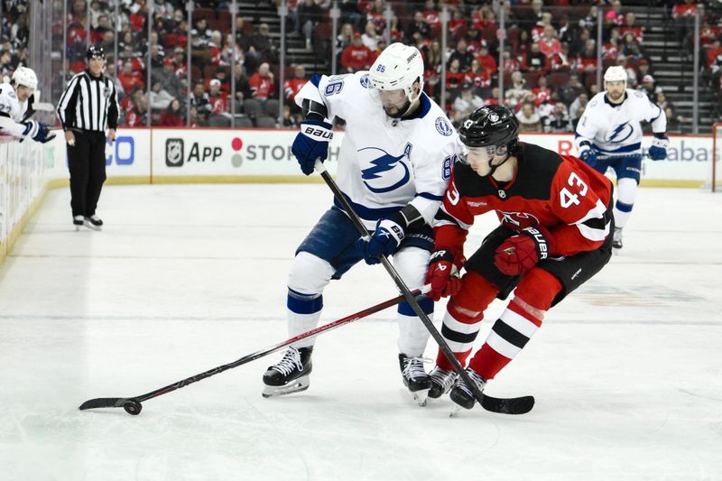 Feb 25, 2024; Newark, New Jersey, USA; New Jersey Devils defenseman Luke Hughes (43) skates with the puck while being defended by Tampa Bay Lightning right wing Nikita Kucherov (86) during the third period at Prudential Center. Mandatory Credit: John Jones-USA TODAY Sports