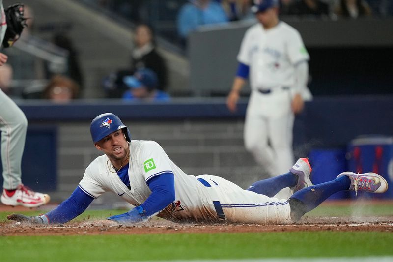 Jun 5, 2025; Toronto, Ontario, CAN; Toronto Blue Jays right fielder George Springer (4) slides into home plate to score against the Philadelphia Phillies on a single by Toronto Blue Jays designated hitter Alejandro Kirk (not pictured) during the sixth inning at Rogers Centre. Mandatory Credit: John E. Sokolowski-Imagn Images