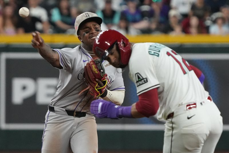 May 18, 2025; Phoenix, Arizona, USA; Colorado Rockies second base Adael Amador (1) turns the double play while avoiding Arizona Diamondbacks outfielder Lourdes Gurriel Jr. (12) in the eighth inning at Chase Field. Mandatory Credit: Rick Scuteri-Imagn Images