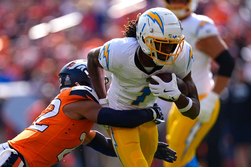 Los Angeles Chargers wide receiver Quentin Johnston (1) runs with the football as Denver Broncos safety Brandon Jones (22) tries to tackle during the first half of an NFL football game, Sunday, Oct. 13, 2024, in Denver. (AP Photo/David Zalubowski)