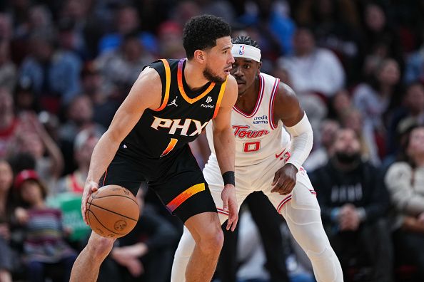 HOUSTON, TEXAS - DECEMBER 27: Devin Booker #1 of the Phoenix Suns dribbles the ball as Aaron Holiday #0 of the Houston Rockets defends during the forth quarter of the game at Toyota Center on December 27, 2023 in Houston, Texas. User expressly acknowledges and agrees that, by downloading and or using this photograph, User is consenting to the terms and conditions of the Getty Images License Agreement. (Photo by Alex Bierens de Haan/Getty Images)