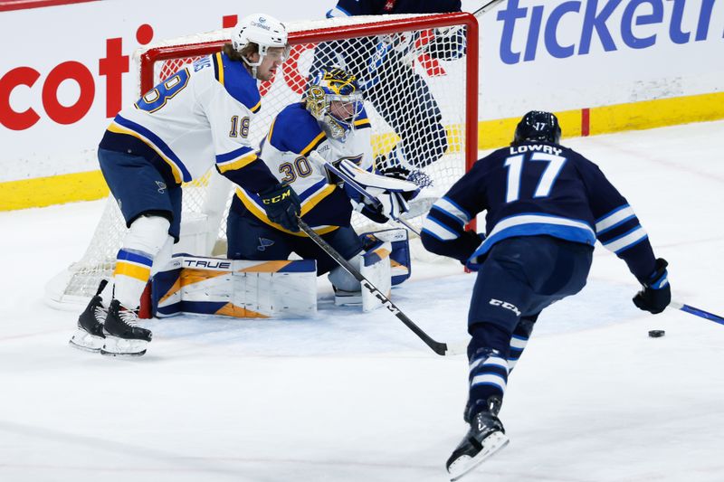 Feb 27, 2024; Winnipeg, Manitoba, CAN; St. Louis Blues goalie Joel Hofer (30), St. Louis Blues forward Robert Thomas (18) and Winnipeg Jets forward Adam Lowry (17) look for the puck during the third period at Canada Life Centre. Mandatory Credit: Terrence Lee-USA TODAY Sports