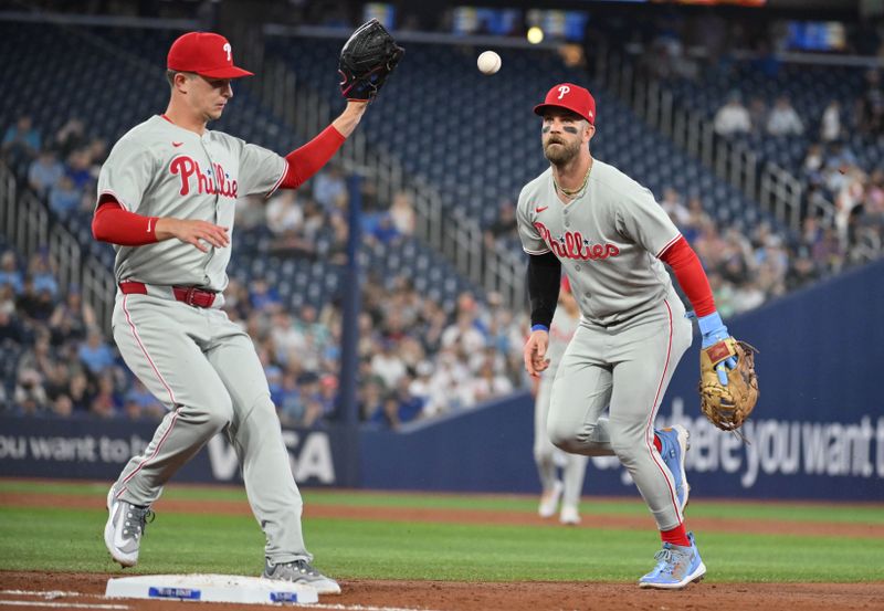 Jun 4, 2025; Toronto, Ontario, CAN;  Philadelphia Phillies first baseman Bryce Harper (3) flips the ball to pitcher Mick Abel (40) to force out Toronto Blue Jays left fielder Alan Roden (not shown) in the third inning at Rogers Centre. Mandatory Credit: Dan Hamilton-Imagn Images