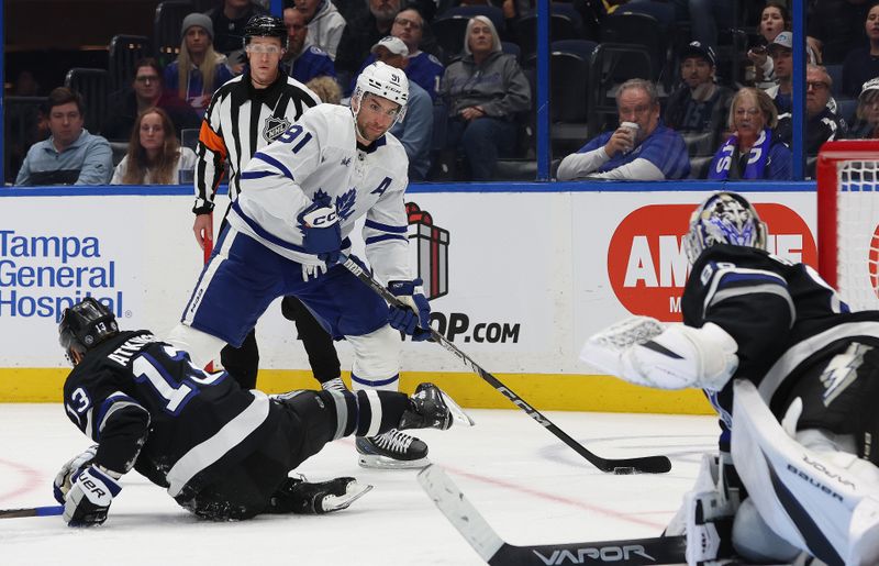 Nov 30, 2024; Tampa, Florida, USA; Toronto Maple Leafs center John Tavares (91) skates with the puck as Tampa Bay Lightning right wing Cam Atkinson (13) defends during the second period at Amalie Arena. Mandatory Credit: Kim Klement Neitzel-Imagn Images