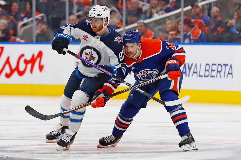 Oct 9, 2024; Edmonton, Alberta, CAN; Edmonton Oilers forward Zach Hyman (18) and Winnipeg Jets forward Kyle Connor (81) battle for a loose puck during the second period at Rogers Place. Mandatory Credit: Perry Nelson-Imagn Images