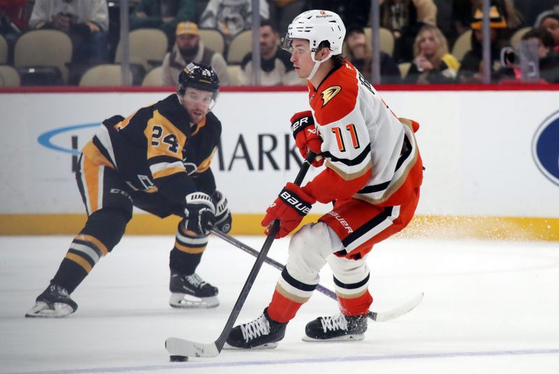 Oct 31, 2024; Pittsburgh, Pennsylvania, USA;  Anaheim Ducks center Trevor Zegras (11) skates with the puck as Pittsburgh Penguins defenseman Matt Grzelcyk (24) defends during the third period at PPG Paints Arena. Mandatory Credit: Charles LeClaire-Imagn Images