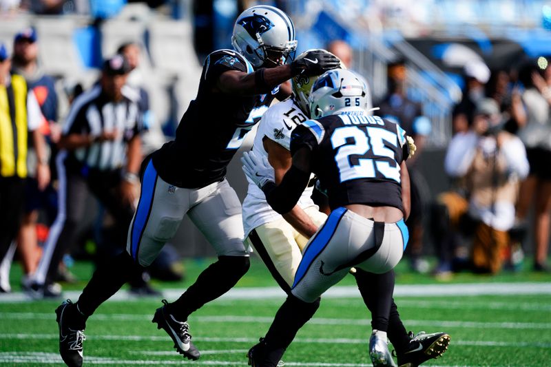 New Orleans Saints wide receiver Chris Olave gets hit by Carolina Panthers cornerback Michael Jackson and safety Xavier Woods during the first half of an NFL football game Sunday, Nov. 3, 2024, in Charlotte, N.C. Olave was taken off the field after getting hurt on the play. (AP Photo/Jacob Kupferman)