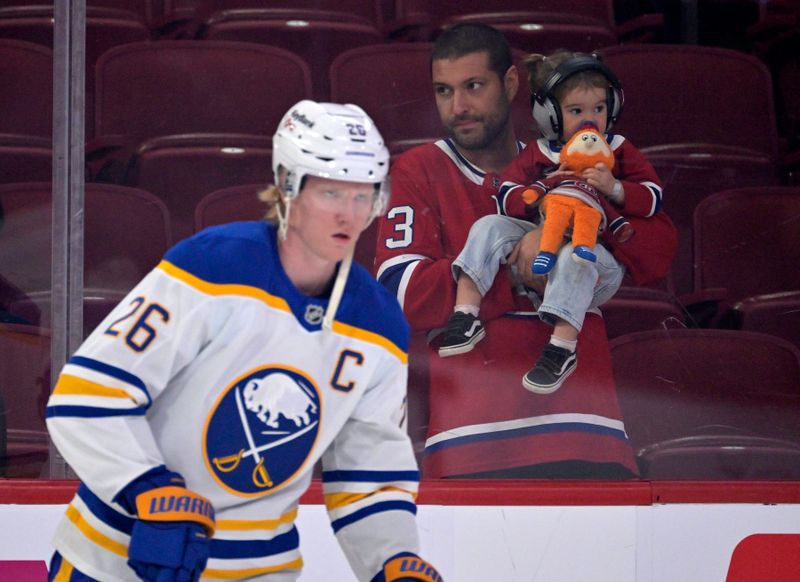 Oct 20, 2025; Montreal, Quebec, CAN; Fan with a child look on as Buffalo Sabres defenseman Rasmus Dahlin (26) skates during the warmup period before the game against the Montreal Canadiens at the Bell Centre. Mandatory Credit: Eric Bolte-Imagn Images