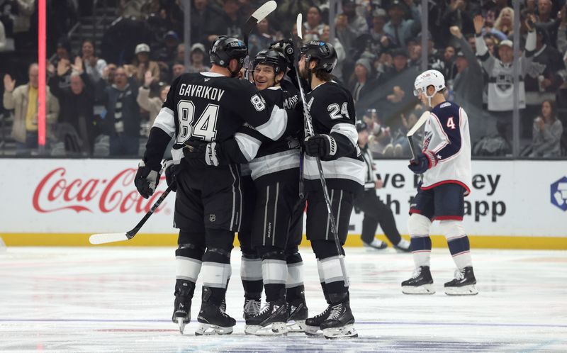 Nov 9, 2024; Los Angeles, California, USA; Los Angeles Kings left wing Trevor Moore (12) celebrates with defenseman Vladislav Gavrikov (84) and center Phillip Danault (24) after scoring during the third period against the Columbus Blue Jackets at Crypto.com Arena. Mandatory Credit: Jason Parkhurst-Imagn Images