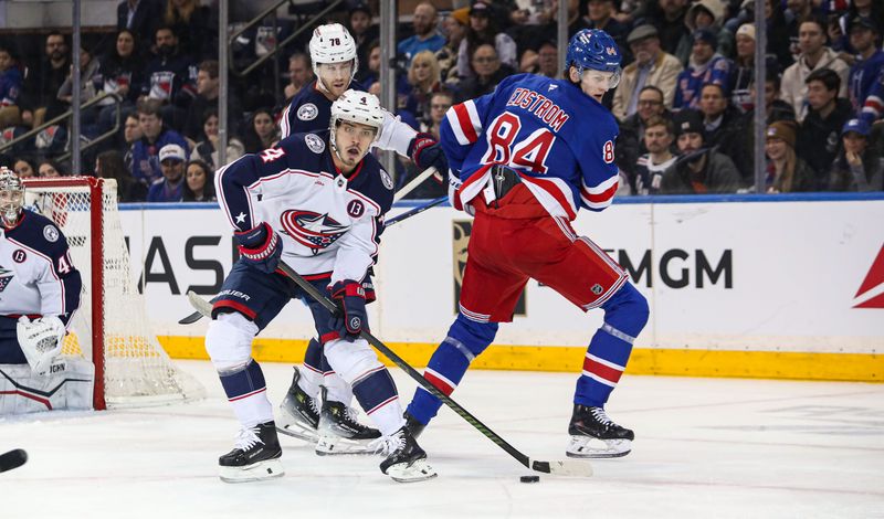 Jan 18, 2025; New York, New York, USA; Columbus Blue Jackets center Cole Sillinger (4) tries to clear the puck in front of New York Rangers center Adam Edstrom (84) during the first period at Madison Square Garden. Mandatory Credit: Danny Wild-Imagn Images