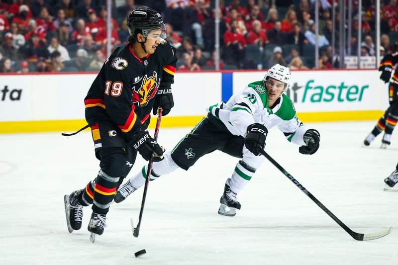 Mar 3, 2026; Calgary, Alberta, CAN; Calgary Flames defenseman Zayne Parekh (19) controls the puck against Dallas Stars center Oskar Bäck (10) during the first period at Scotiabank Saddledome. Mandatory Credit: Sergei Belski-Imagn Images