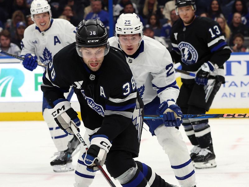 Nov 30, 2024; Tampa, Florida, USA; Tampa Bay Lightning left wing Brandon Hagel (38) skates with the puck as Toronto Maple Leafs right wing Pontus Holmberg (29) defends during the second period at Amalie Arena. Mandatory Credit: Kim Klement Neitzel-Imagn Images