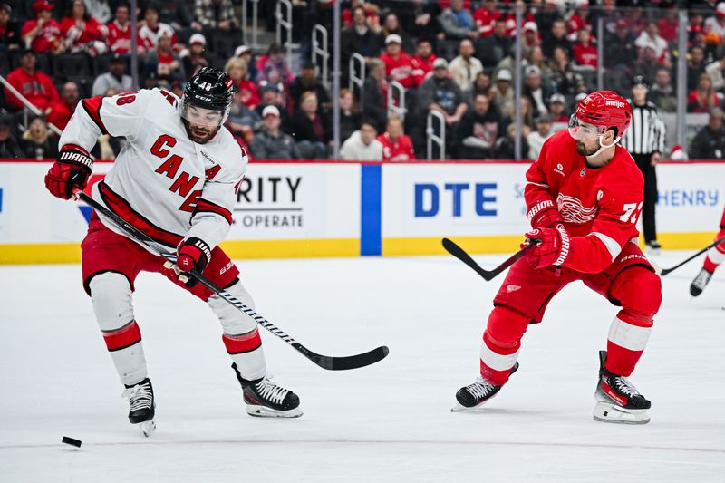 Apr 4, 2025; Detroit, Michigan, USA; Carolina Hurricanes left wing Jordan Martinook (48) and Detroit Red Wings center Dylan Larkin (71) battle for the puck during the second period at Little Caesars Arena. Mandatory Credit: Tim Fuller-Imagn Images