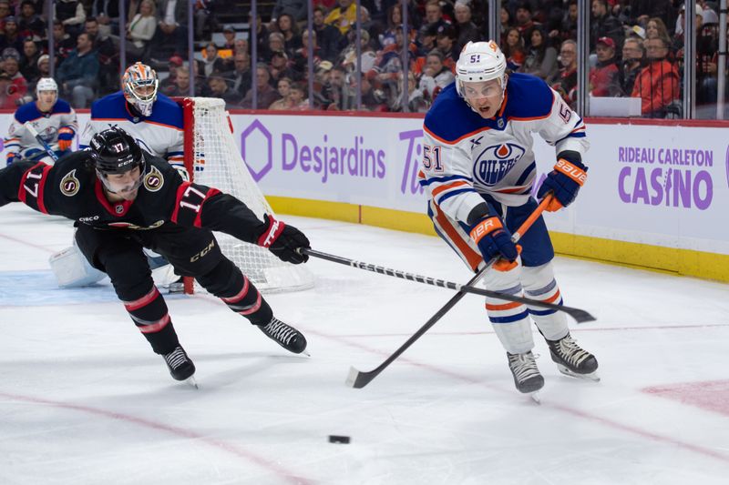 Nov 19, 2024; Ottawa, Ontario, CAN; Edmonton Oilers defenseman Troy Stecher (51) moves the puck away from Ottawa Senators right wing Zack MacEwen (17) in the first period at the Canadian Tire Centre. Mandatory Credit: Marc DesRosiers-Imagn Images