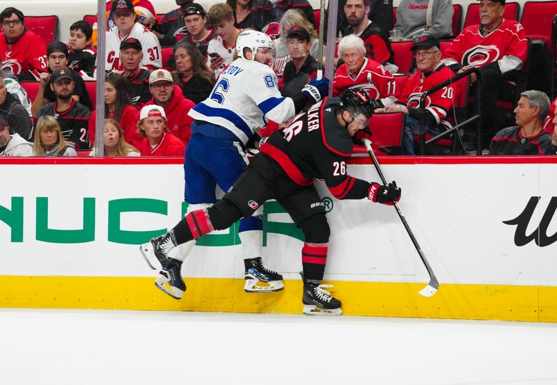 Oct 11, 2024; Raleigh, North Carolina, USA;  Carolina Hurricanes defenseman Sean Walker (26) checks Tampa Bay Lightning right wing Nikita Kucherov (86) during the second period at PNC Arena. Mandatory Credit: James Guillory-Imagn Images