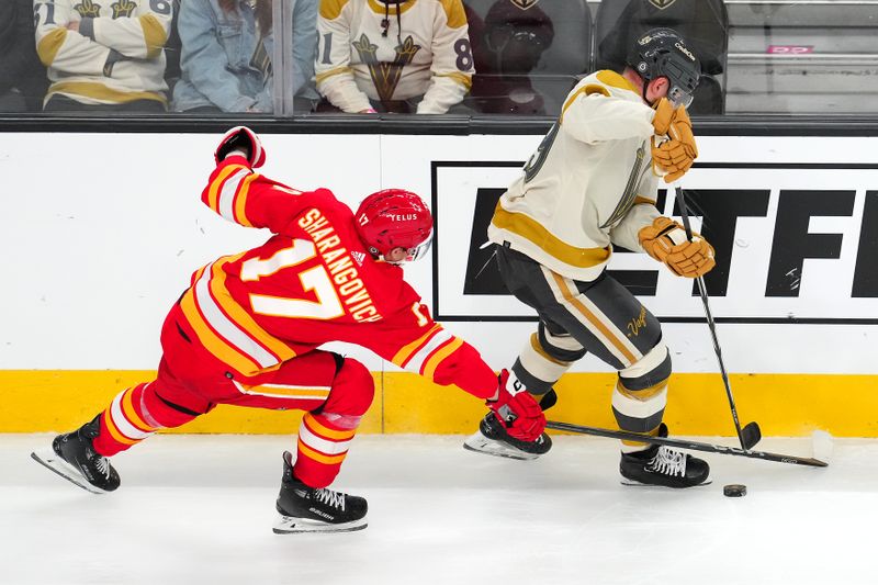 Jan 13, 2024; Las Vegas, Nevada, USA; Calgary Flames center Yegor Sharangovich (17) steals the puck from Vegas Golden Knights center Ivan Barbashev (49) during the third period at T-Mobile Arena. Mandatory Credit: Stephen R. Sylvanie-USA TODAY Sports