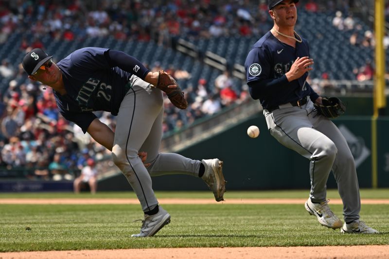 May 26, 2024; Washington, District of Columbia, USA; Seattle Mariners first baseman Ty France (23) attempts to toss the ball between his legs to starting pitcher Bryan Woo (22) against the Washington Nationals during the seventh inning at Nationals Park. Mandatory Credit: Rafael Suanes-USA TODAY Sports