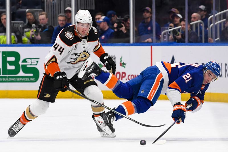 Dec 13, 2023; Elmont, New York, USA; New York Islanders center Kyle Palmieri (21) falls to the ice as Anaheim Ducks left wing Ross Johnston (44) goes after the loose puck during the first period at UBS Arena. Mandatory Credit: Dennis Schneidler-USA TODAY Sports