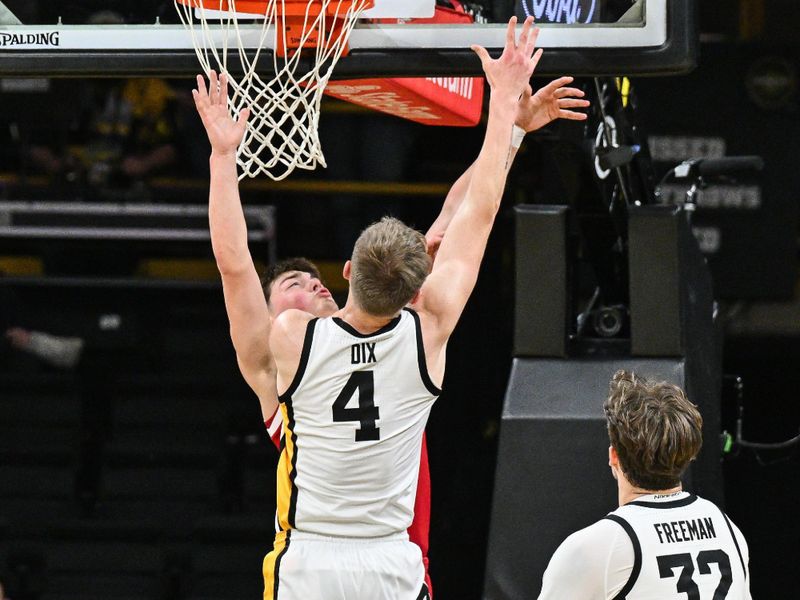 Jan 7, 2025; Iowa City, Iowa, USA; Iowa Hawkeyes guard Josh Dix (4) goes to the basket as Nebraska Cornhuskers guard Connor Essegian (0) defends and forward Owen Freeman (32) looks on during the first half at Carver-Hawkeye Arena. Mandatory Credit: Jeffrey Becker-Imagn Images