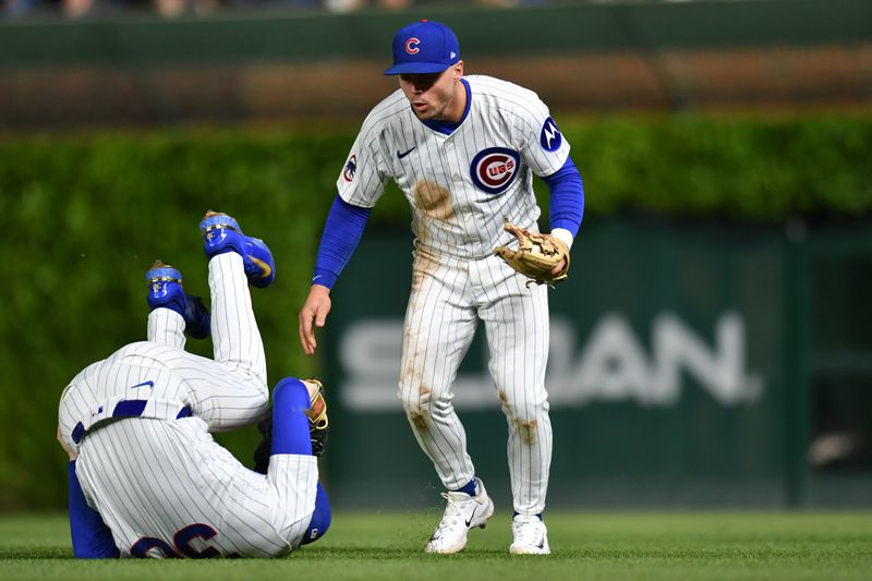 May 27, 2025; Chicago, Illinois, USA; Chicago Cubs second baseman Nico Hoerner (right) catches a fly ball and collides with right fielder Kyle Tucker (left) during the seventh inning against the Colorado Rockies at Wrigley Field. Mandatory Credit: Patrick Gorski-Imagn Images