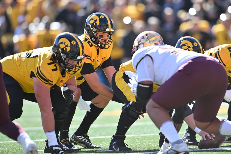 Oct 21, 2023; Iowa City, Iowa, USA; Iowa Hawkeyes quarterback Deacon Hill (10) directs the offense as offensive lineman Connor Colby (77) and offensive lineman Rusty Feth (60) prepare to block against the Minnesota Golden Gophers during the first quarter at Kinnick Stadium. Mandatory Credit: Jeffrey Becker-USA TODAY Sports