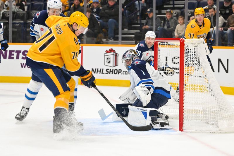Nov 29, 2025; Nashville, Tennessee, USA;  Winnipeg Jets goaltender Eric Comrie (1) makes a save against Nashville Predators right wing Matthew Wood (71) during the first period at Bridgestone Arena. Mandatory Credit: Steve Roberts-Imagn Images