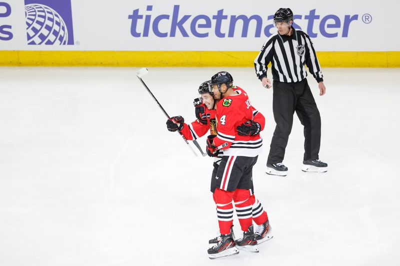 Mar 26, 2024; Chicago, Illinois, USA; Chicago Blackhawks defenseman Seth Jones (4) celebrates with center Philipp Kurashev (23) after scoring against the Calgary Flames during the first period at United Center. Mandatory Credit: Kamil Krzaczynski-USA TODAY Sports