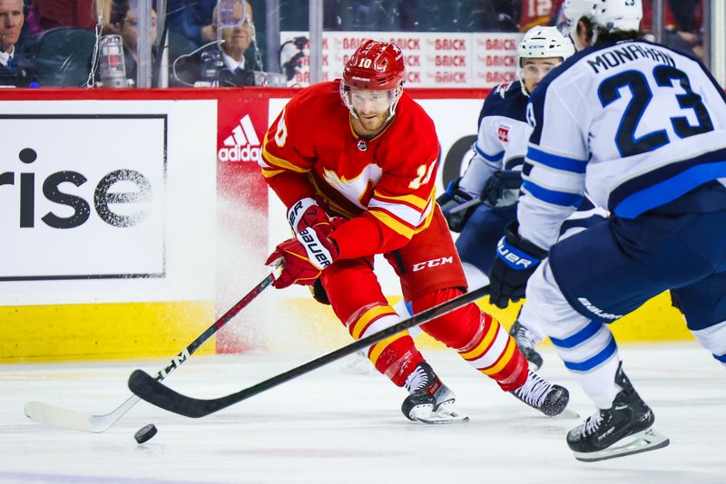 Feb 19, 2024; Calgary, Alberta, CAN; Calgary Flames center Jonathan Huberdeau (10) controls the puck against Winnipeg Jets center Sean Monahan (23) during the first period at Scotiabank Saddledome. Mandatory Credit: Sergei Belski-USA TODAY Sports