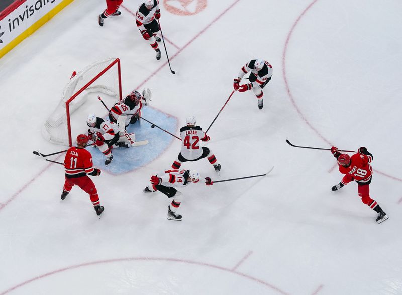 Oct 15, 2024; Raleigh, North Carolina, USA;  Carolina Hurricanes center Jack Drury (18) takes shot on New Jersey Devils goaltender Jacob Markstrom (25) during the second period at PNC Arena. Mandatory Credit: James Guillory-Imagn Images