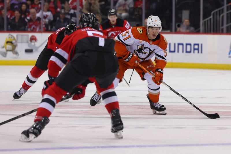 Oct 27, 2024; Newark, New Jersey, USA; Anaheim Ducks defenseman Olen Zellweger (51) skates with the puck while being defended by New Jersey Devils defenseman Brenden Dillon (5) during the first period at Prudential Center. Mandatory Credit: Ed Mulholland-Imagn Images