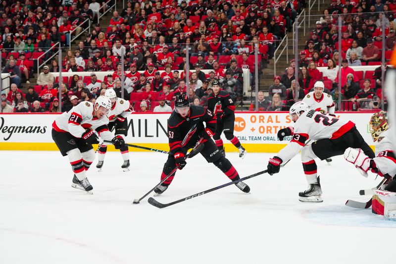 Nov 16, 2024; Raleigh, North Carolina, USA;  Carolina Hurricanes center Jack Drury (18) skates with the puck between Ottawa Senators defenseman Travis Hamonic (23) and center Nick Cousins (21) during the first period at Lenovo Center. Mandatory Credit: James Guillory-Imagn Images