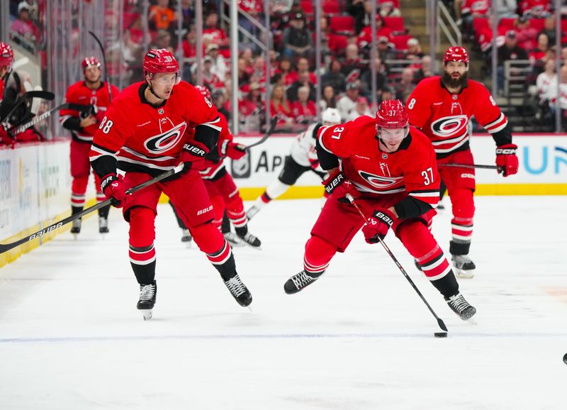 Oct 15, 2024; Raleigh, North Carolina, USA;  Carolina Hurricanes right wing Andrei Svechnikov (37) skates up the ice with the puck with center Martin Necas (88) against the New Jersey Devils  during the first period at PNC Arena. Mandatory Credit: James Guillory-Imagn Images